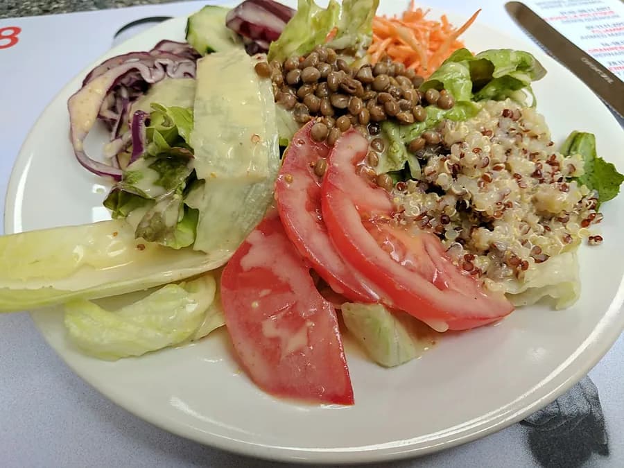 Une grande salade composée du Massala Gourmand : quinoa, lentilles, tomates, salade verte et carottes, servie à Genève.