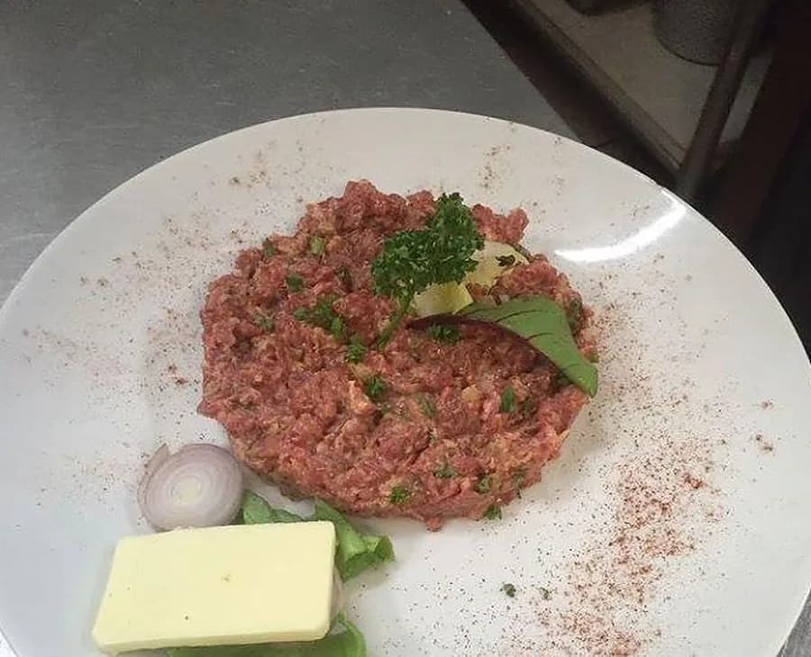Un tartare de bœuf coupé au couteau, persillé, servi avec beurre et oignon au Massala Gourmand, Genève.